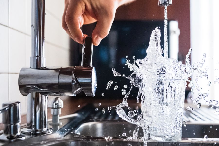 Filling a water glass from the tap after service from Water Softener Companies in San Antonio, TX.