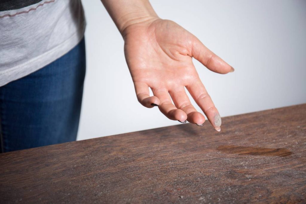 Close-up of dust on a person's finger after touching a dusty surface