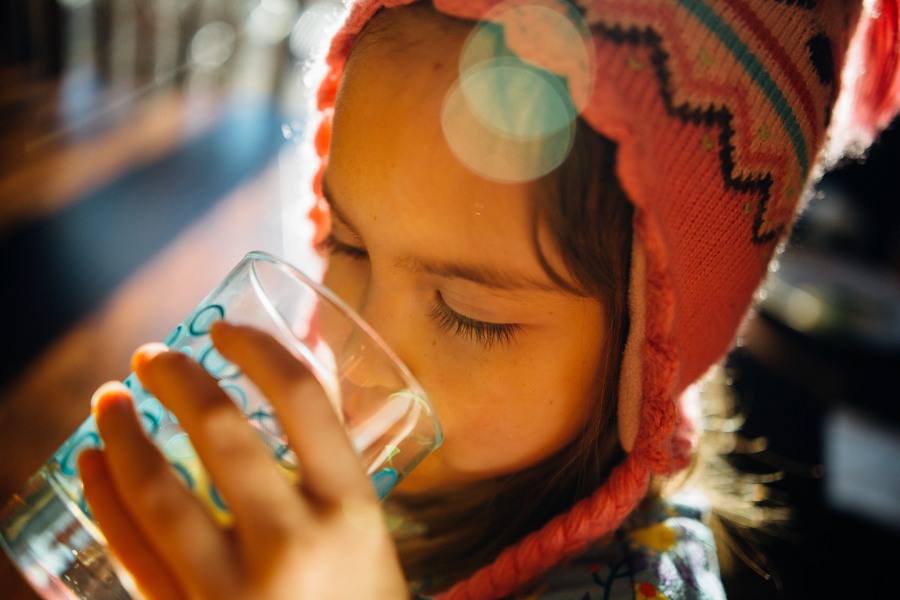 A young child drinking water from a glass