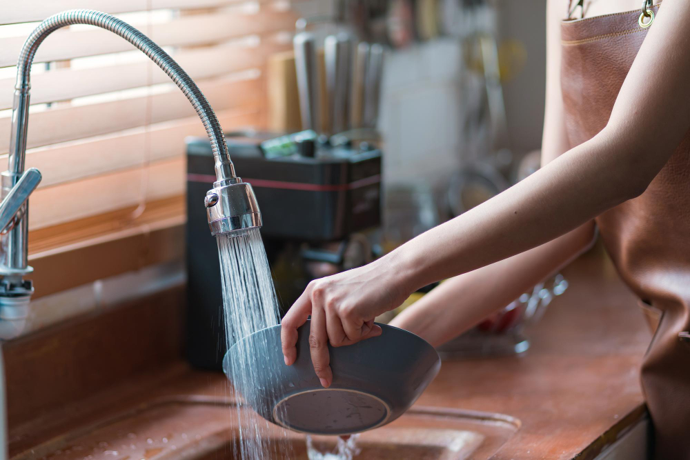 A woman washing a bowl in a sink, showing how water softener